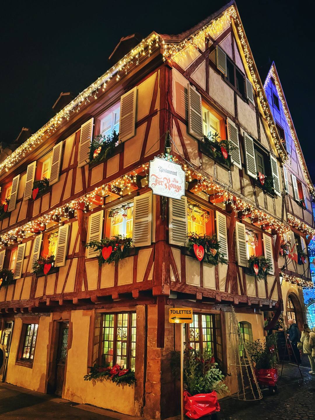 Half-timbered house lit up and decorated for Christmas in Colmar, Alsace, at nightfall
